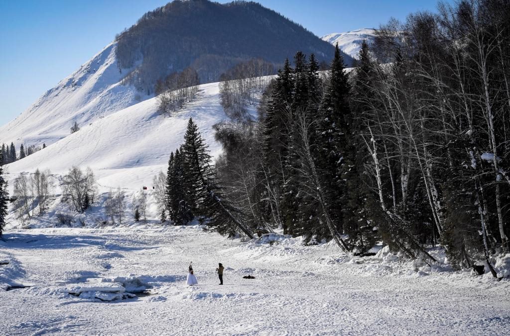 2024年2月5日，兩名游客在新疆阿勒泰地區(qū)布爾津縣禾木村拍照。新華社記者 馬鍇 攝