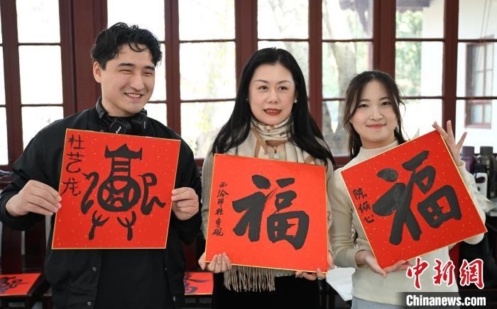 1月20日，外籍留學(xué)生和西泠印社社員李硯(中)展示各自創(chuàng)作的福貼。當(dāng)日，來(lái)自巴西、馬來(lái)西亞、加納、哈薩克斯坦的外籍留學(xué)生在浙江杭州西泠印社體驗(yàn)福貼、春聯(lián)和篆刻，感受古老的中國(guó)傳統(tǒng)文化。中新社記者 王剛 攝
