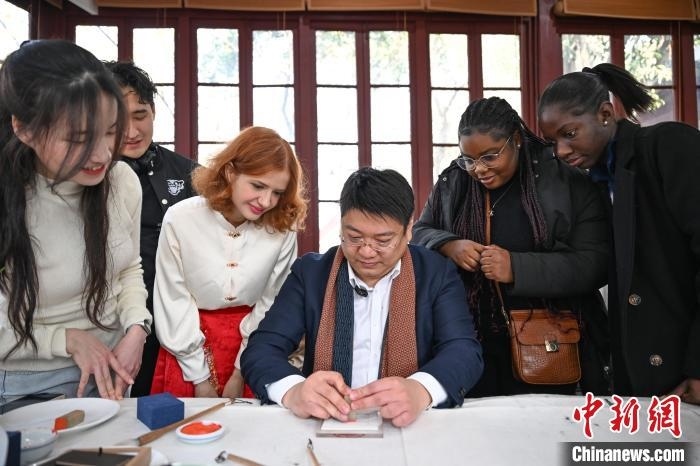 1月20日，篆刻家王臻向外籍留學(xué)生展示篆刻印章。當(dāng)日，來(lái)自巴西、馬來(lái)西亞、加納、哈薩克斯坦的外籍留學(xué)生在浙江杭州西泠印社體驗(yàn)福貼、春聯(lián)和篆刻，感受古老的中國(guó)傳統(tǒng)文化。中新社記者 王剛 攝