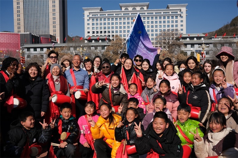 中外青年學(xué)子在安塞文化廣場(chǎng)觀看陜北腰鼓和大秧歌表演后合影留念，大家踏著鼓點(diǎn)共舞，翻飛的紅綢與躍動(dòng)的身影交織，在黃土地廣場(chǎng)上繪出一幅生動(dòng)的陜北民俗互動(dòng)畫(huà)卷