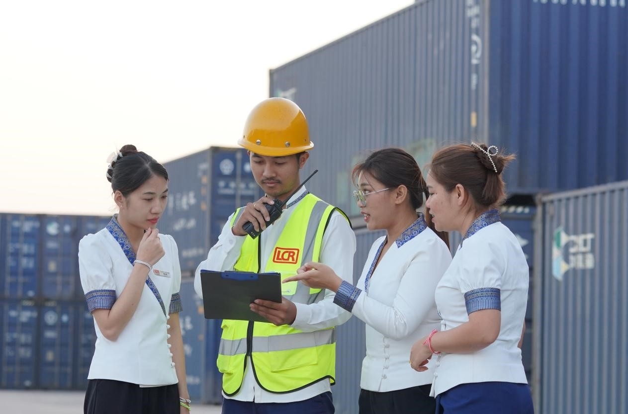 萬象南站貨運(yùn)值班員陳尼啦（左一）與同事在一起討論工作。老中鐵路有限公司供圖