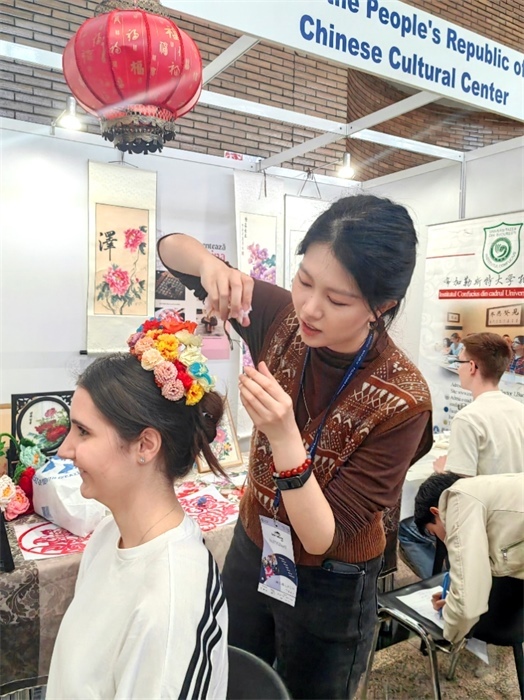 展覽正值羅馬尼亞迎春花節(jié)，國際中文教師志愿者潘婧穎向游客們介紹了國家非物質(zhì)文化遺產(chǎn)——福建泉州的簪花文化。布加勒斯特大學孔子學院供圖。