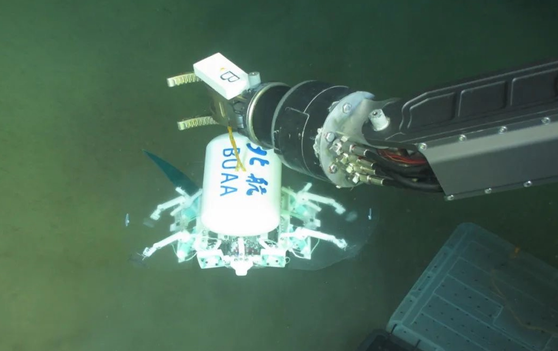 科研人員利用機械臂將北航深海小型機器人投于馬里亞納海溝。校方供圖