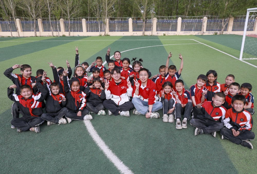 4月23日，在新疆克州阿圖什市哈拉峻鄉(xiāng)謝依特小學(xué)，支教教師王俊文（中左）、李軻凡（中右）和學(xué)生在一起。