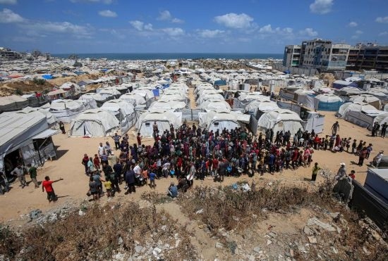 5月28日，人們?cè)诩由吵俏鞑康纳程犭y民營(yíng)等待領(lǐng)取救助食物。新華社發(fā)（里澤克·阿卜杜勒賈瓦德攝）